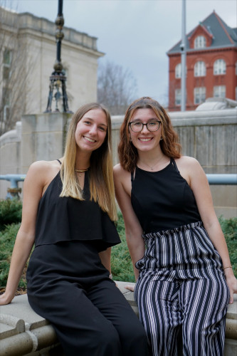 Two women sit closely together and smile for the camera.