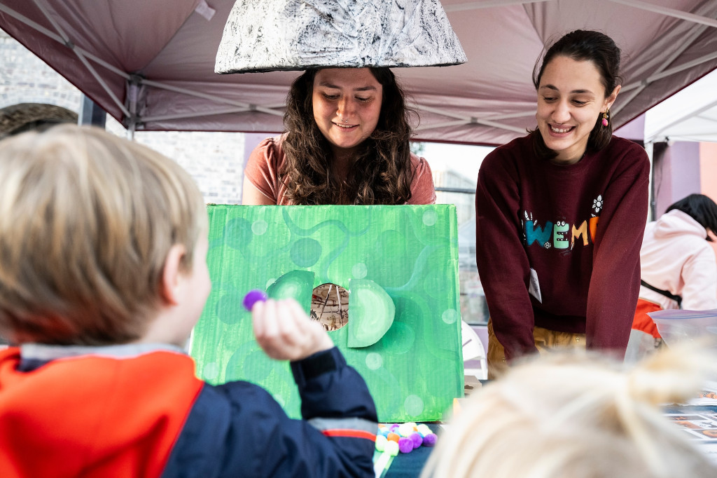 A woman wearing a cap that appears like the top of a mushroom plays a game with a child.