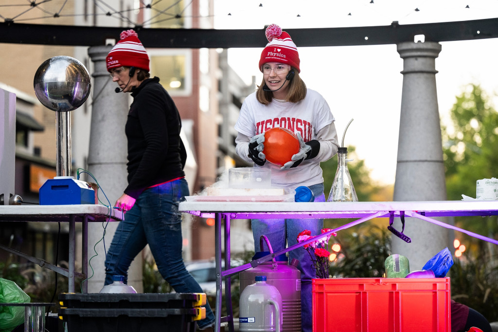 Two women hold up frozen balloons.