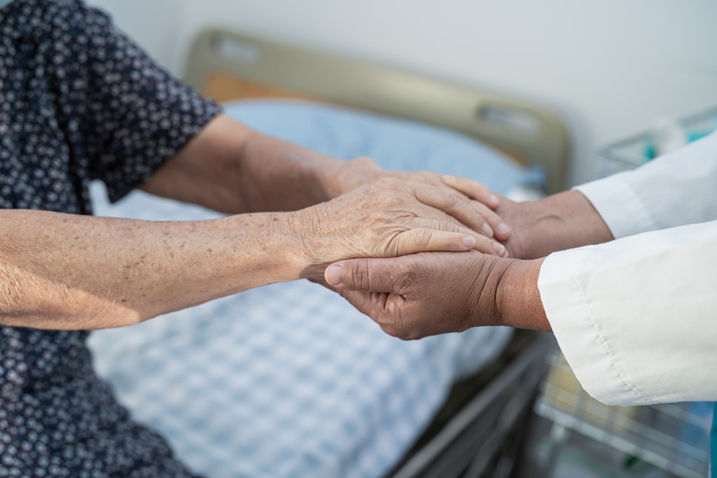 Two pairs of hands clutch each other; one of them appearing to belong to an elderly person.