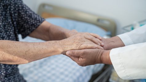 Two pairs of hands clutch each other; one of them appearing to belong to an elderly person.