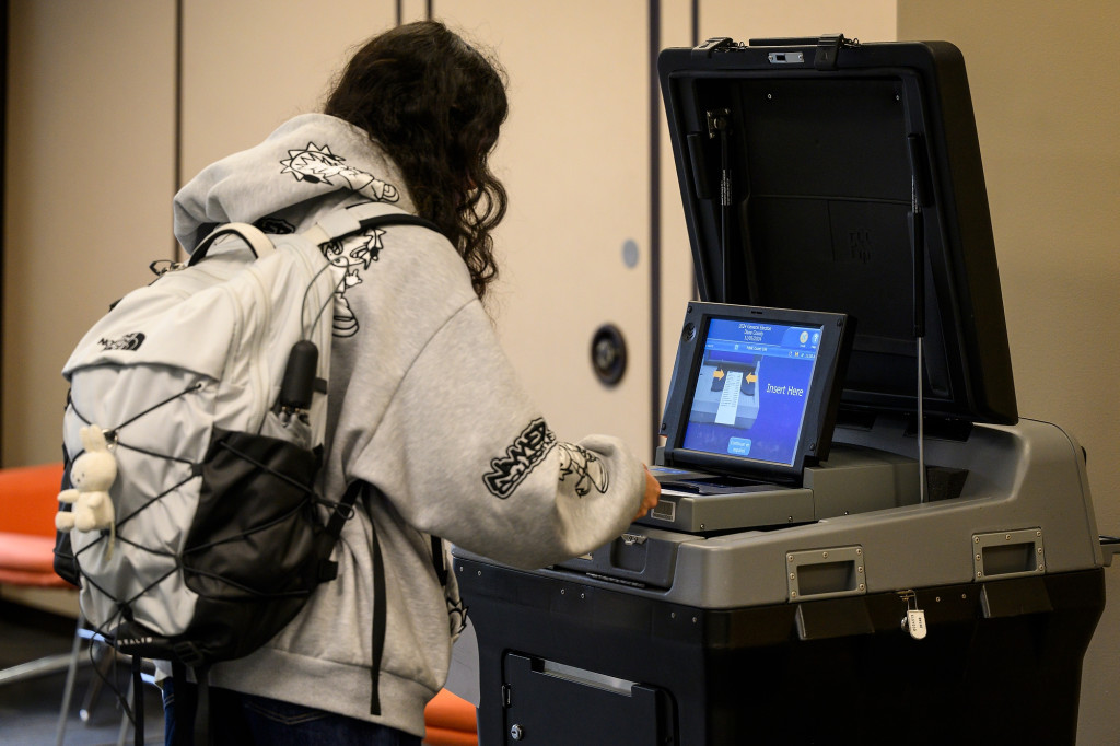 A woman submits a ballot to a machine tabulator.