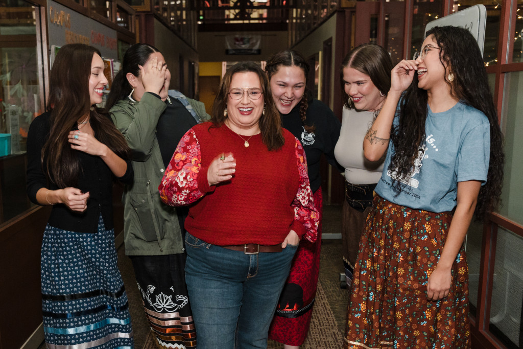 A group of young women students stands around comedian Jana Schmieding and laugh before posing for a photo.