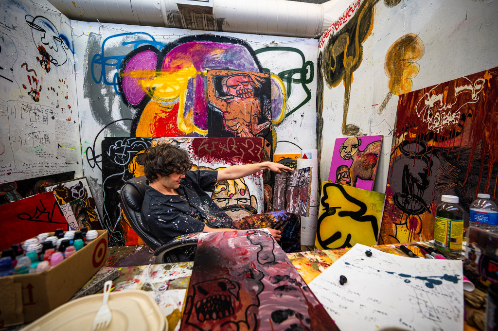 A person sits at a desk and is surrounded by colorful artwork.