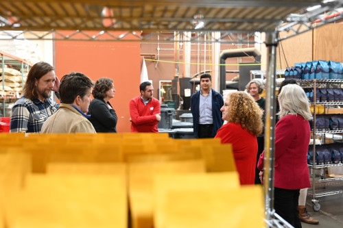 Several people walk on the floor of a warehouse building.