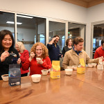 People sit around a table sipping coffee.