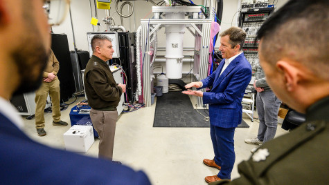 Two men speak to each other in a room full of equipment.