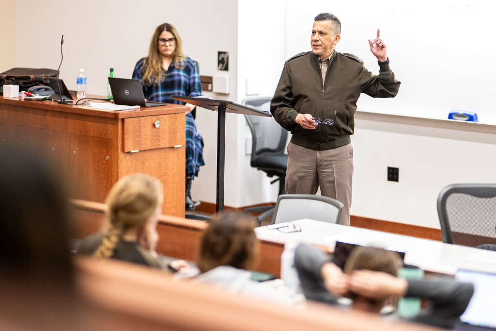 A man speaks in front of a classroom of people.