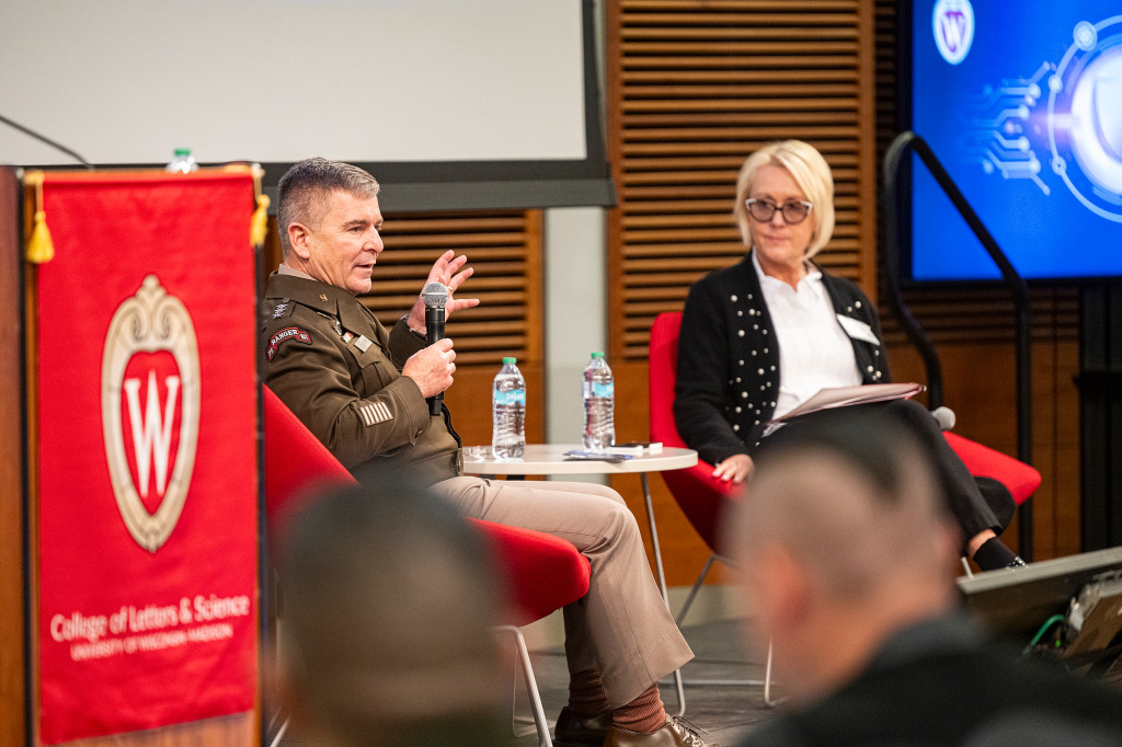 A man and a woman sitting in chairs talk.