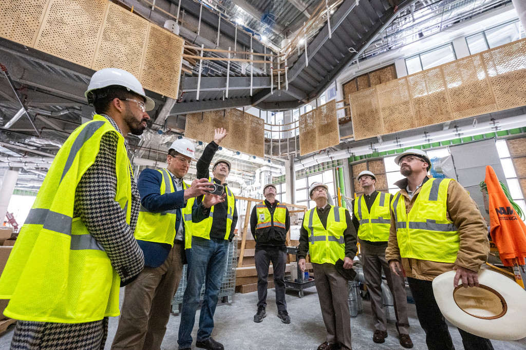 A group of people wearing yellow safety visits tour in a large room.