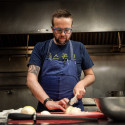 A man slices vegetables on a counter in a kitchen setting.
