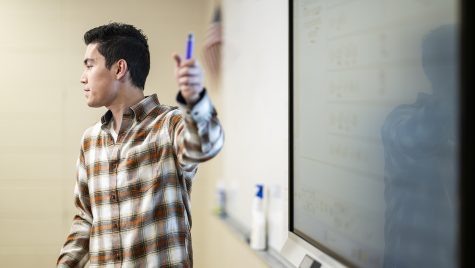 Reed Trueblood gestures with a dry erase marker in front of a whiteboard in his math classroom.