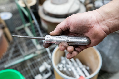 A hand holds a screwdriver with a metal handle.