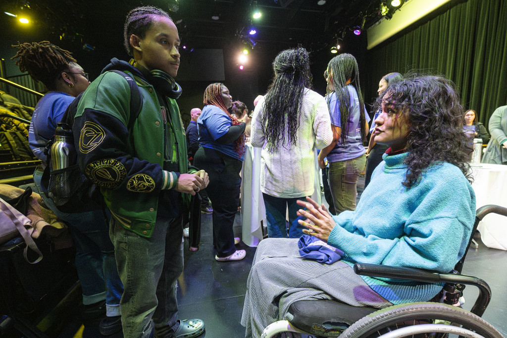 A woman in a wheelchair talks to several people gathered around her.