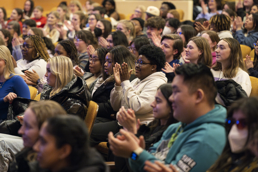 People are shown in an audience, clapping.