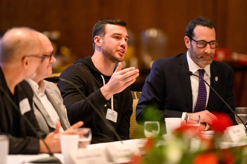 A man sitting on a panel gestures as he talks.