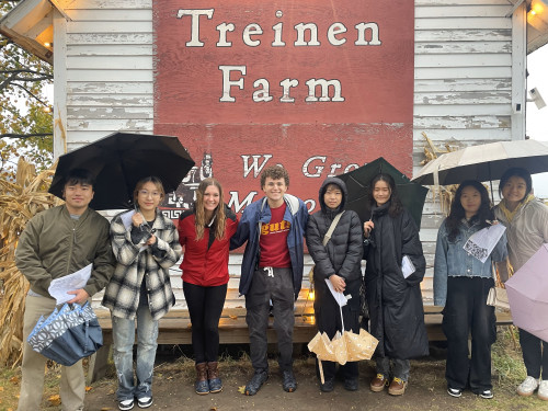 A group of people gather in from of a sign reading "Treinen Farm."