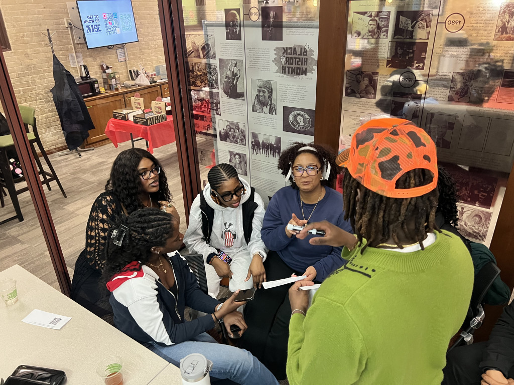 A group sitting in a circle in their chairs discuss the clues presented during the scavenger hunt.