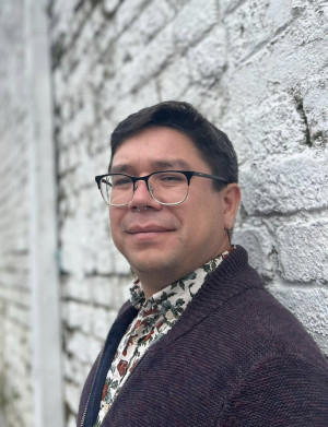 Portrait of UW history professor Jorell Meléndez-Badillo on a white brick background.