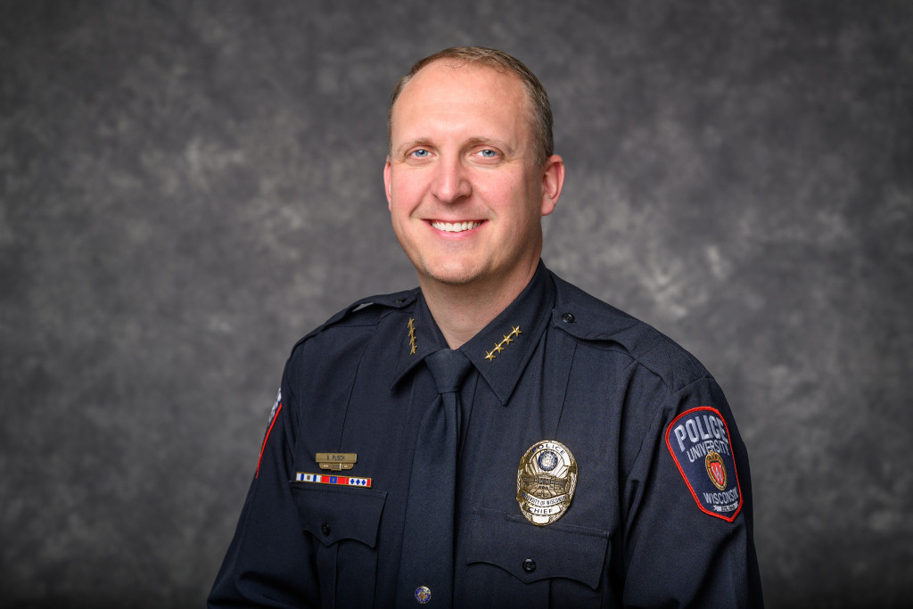 A man in a police uniform smiles at the camera.