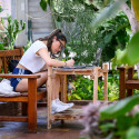 A woman studies amid a number of plants.