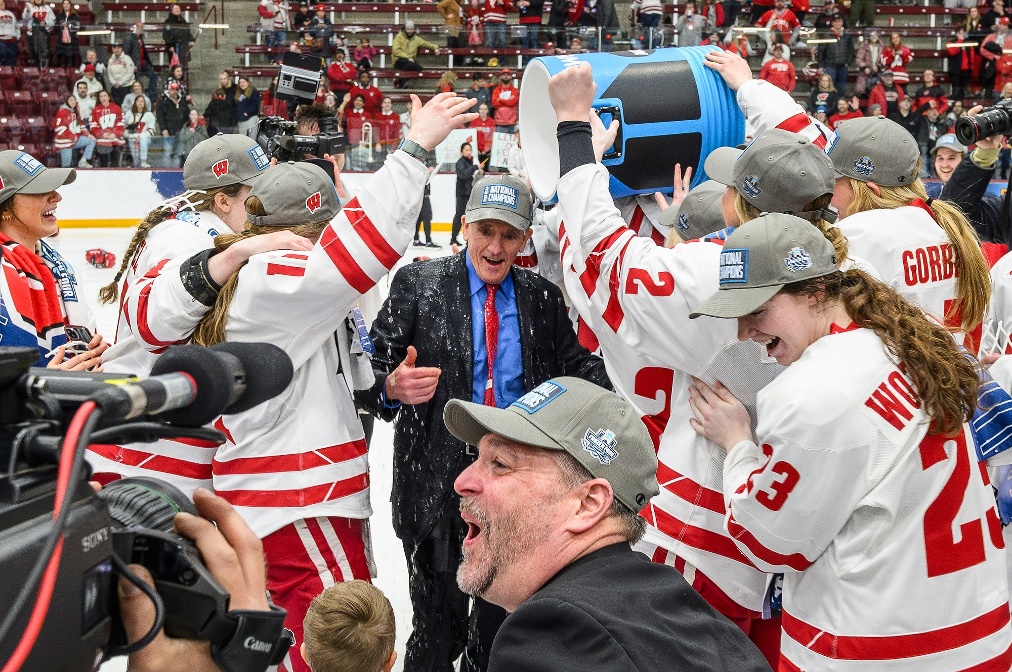 A group of Badger hockey players surround Coach Johnson and dump a large cooler of Gatorade over his head.