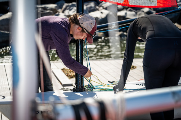 Two people work to arrange ropes on a sailboat.