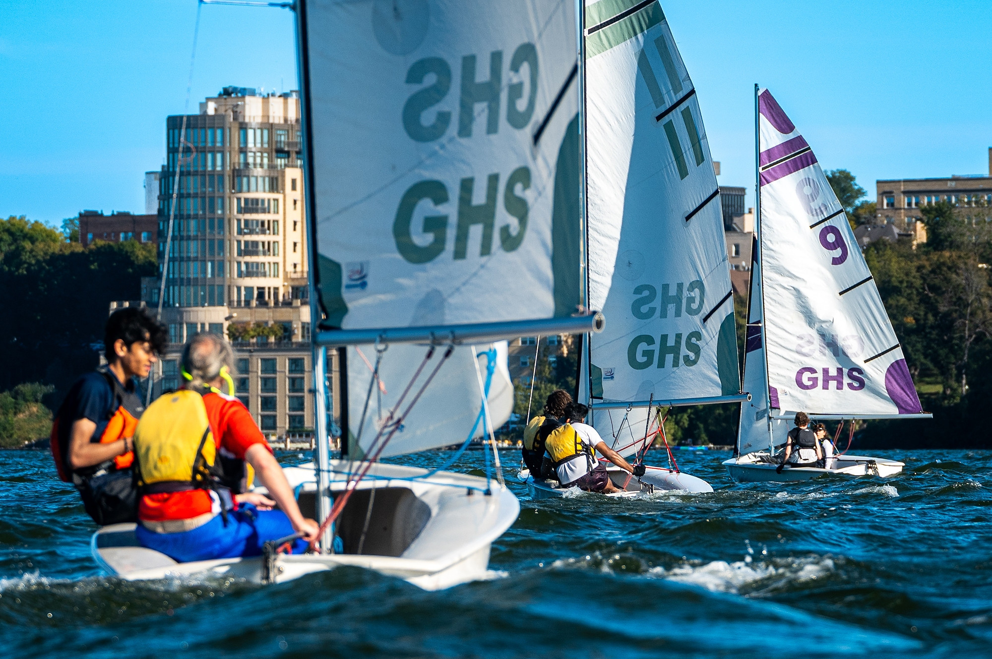 A group of sailboats are gathered at a starting line for a race.
