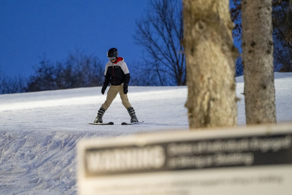 A person skis down a slope with his skis turned inward.