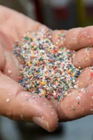 A hand holds colorful sand-like grains