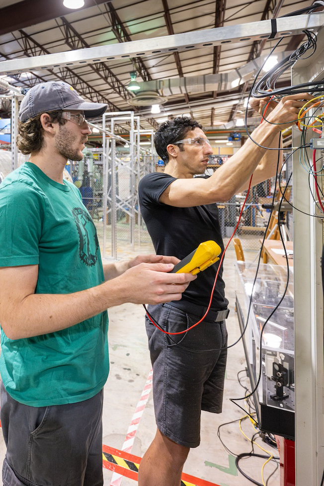 Two people work on a piece of technical equipment
