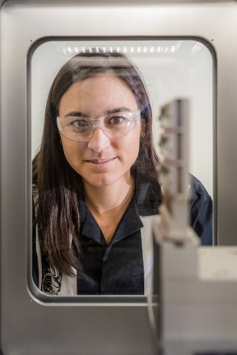 A scientist wearing protective eyewear loos into a lab chamber