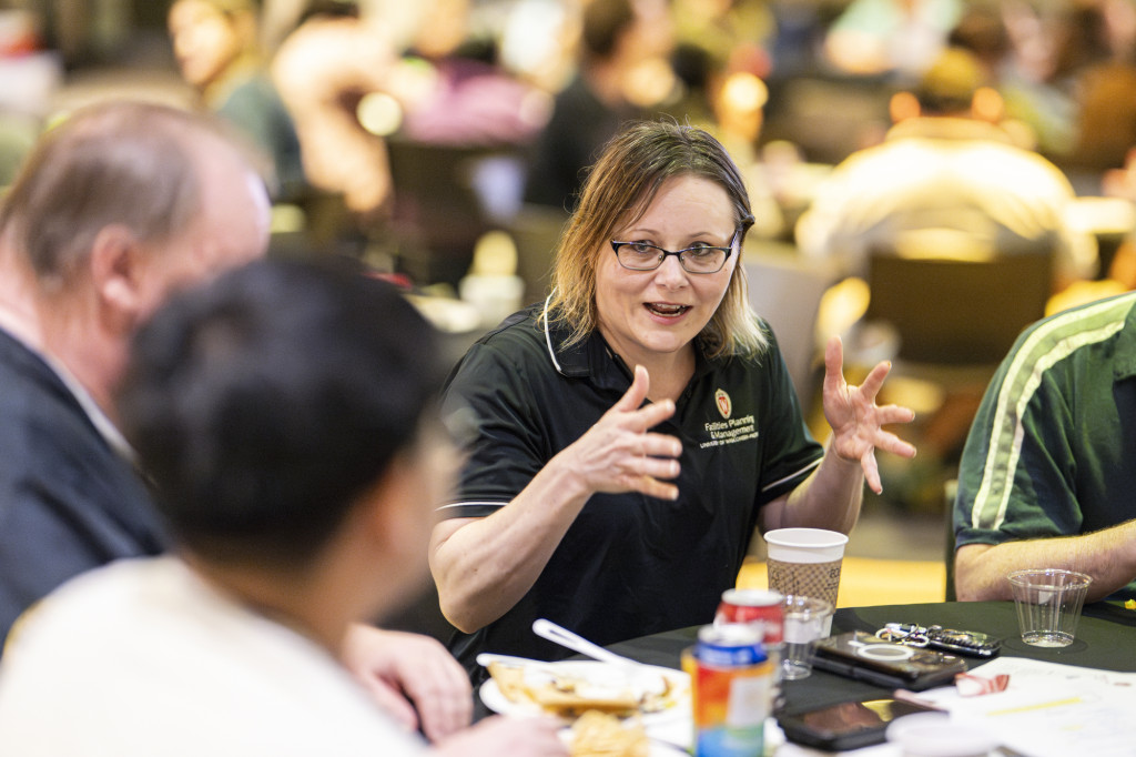A closeup of a woman talking with fellow employees at her table.