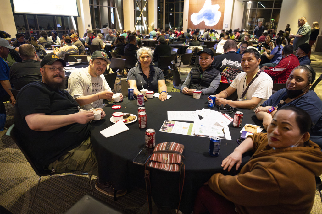 A group of employees sit around a round table and look at the camera for a photo.