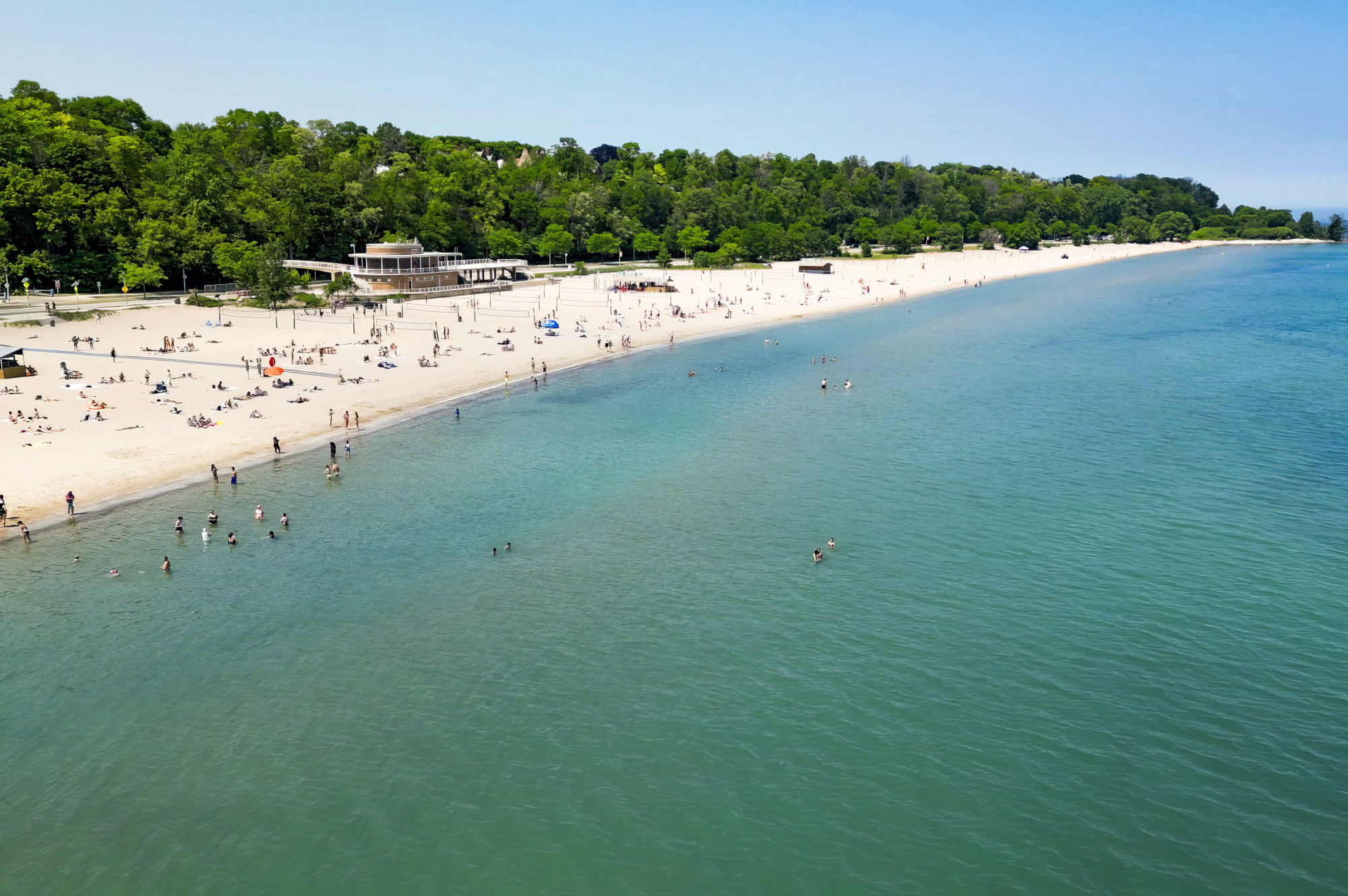 An aerial view of a beach along Wisconsin's coast. People play in the water while others lay on the sandy beach.