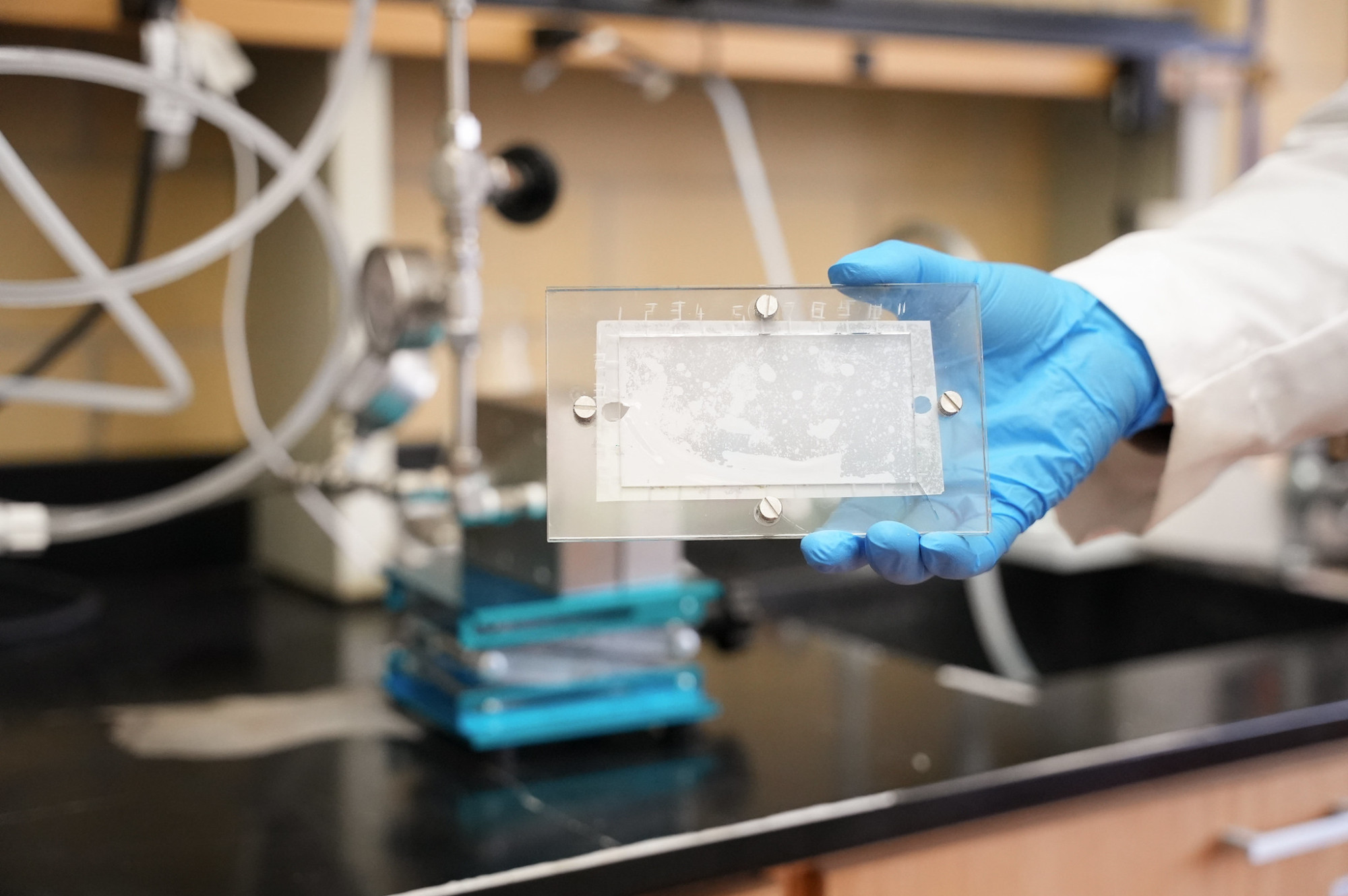 A gloved hand holds up a sample of the semipermeable membrane.