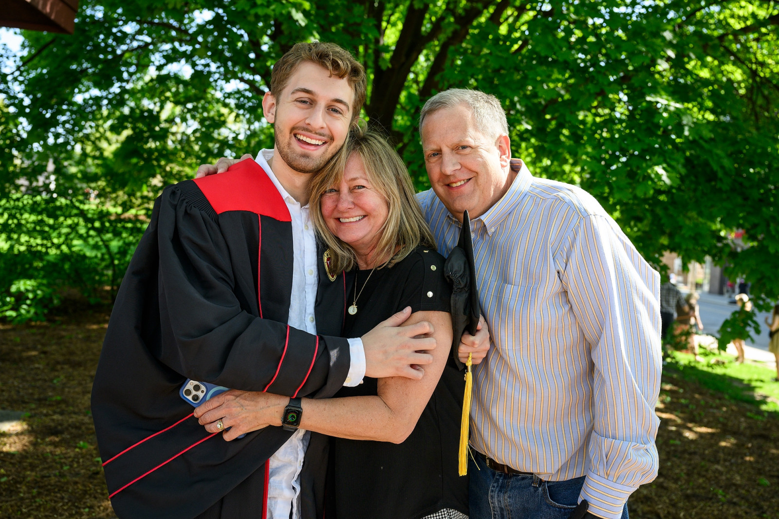 A graduate hugs his beaming mother and father outside Camp Randall.