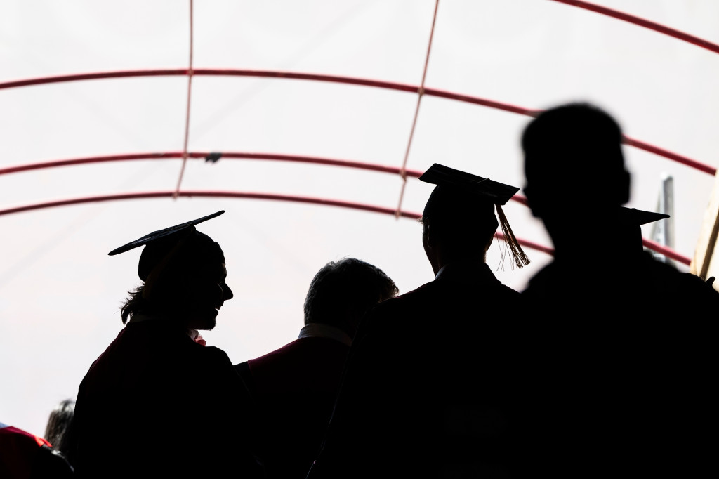 People in graduation gowns are seen walking.