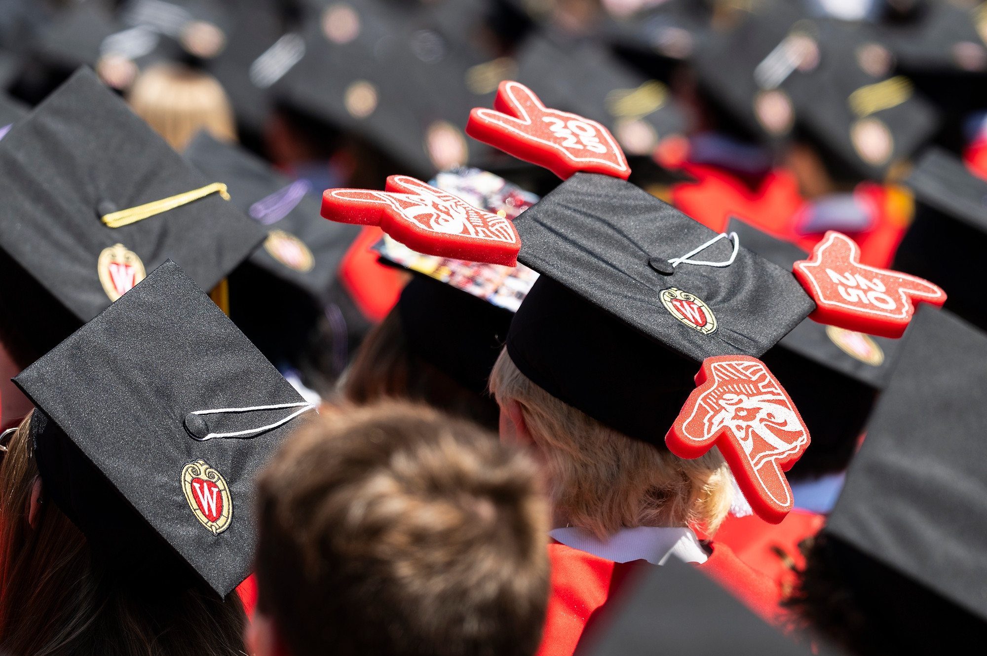 Seen from the back, a graduate wears a cap with small foam fingers attached to each point.