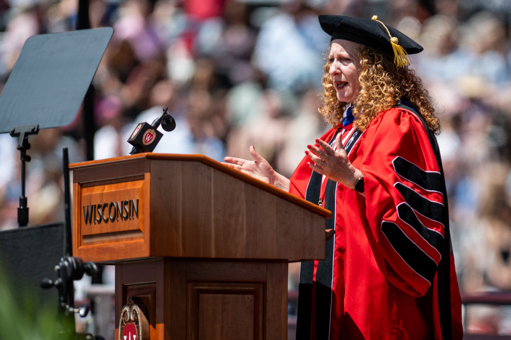 Chancellor Mnookin speaks at a podium. She's wearing a red and black doctoral robe and velvet cap.