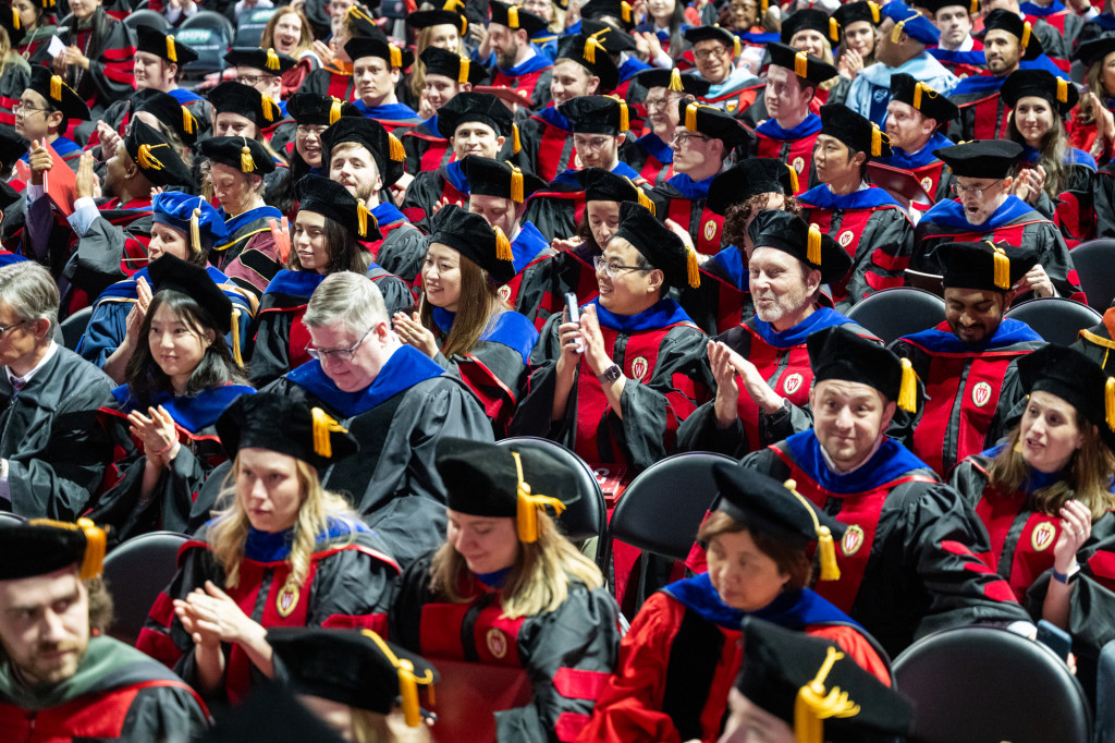 Photo shows stands full of people wearing academic gown and smiling.