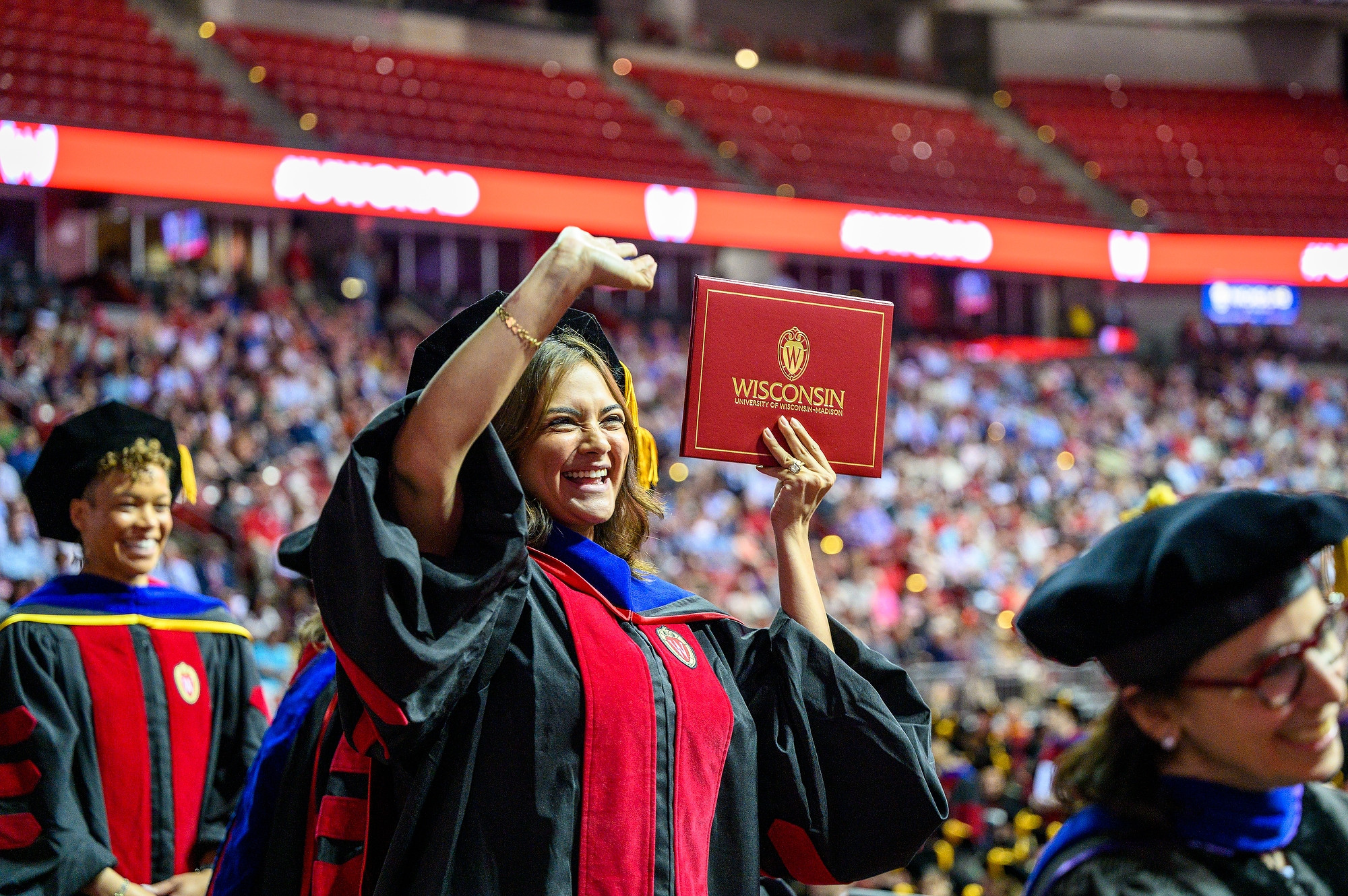 A new graduate smiles and points to her diploma.