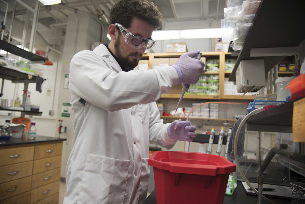 Researcher Thomas Anderson, wearing a lab coat and safety goggles, works with a sample.