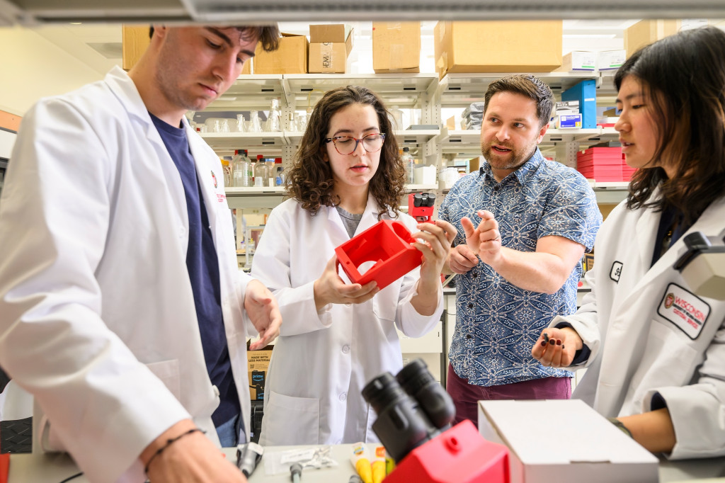 A man works in a lab with three other people.