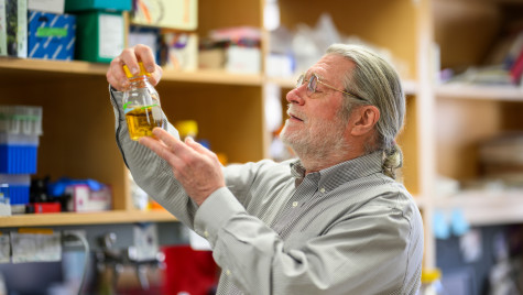 Brian Fox inspects a liquid specimen in a glass container.