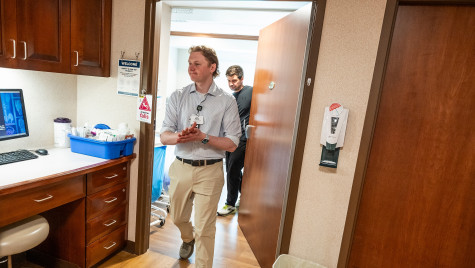 Hoffman walks into a treatment room at Aurora Medical Center–Manitowoc County followed closely by Leiknes whose hand remains on the door of the treatment room as he pulls it shut. As they enter, they are greeted by dimmer lights and a computer that partially shows x-rays of an unidentified patient.