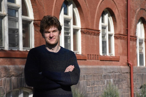 Jack Ohly stands for a portrait photo outside Science Hall, a red brick building on the UW–Madison campus