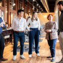 Five people stand in conversation while touring a salon.