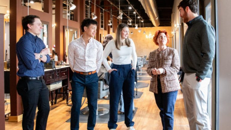 Five people stand in conversation while touring a salon.
