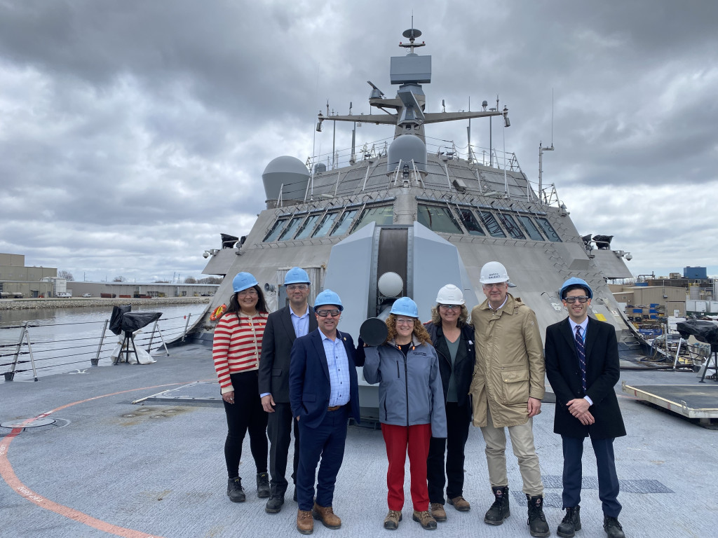 People stand in front of a big boat.
